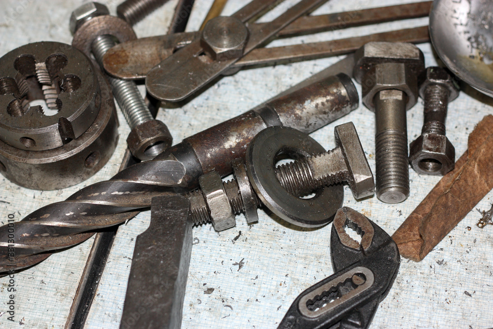 Bolts, nuts, drill and tool on the table. Rusty metal. Side view. Bolts, nuts, drill and tool on the table. Rusty metal. Side view.