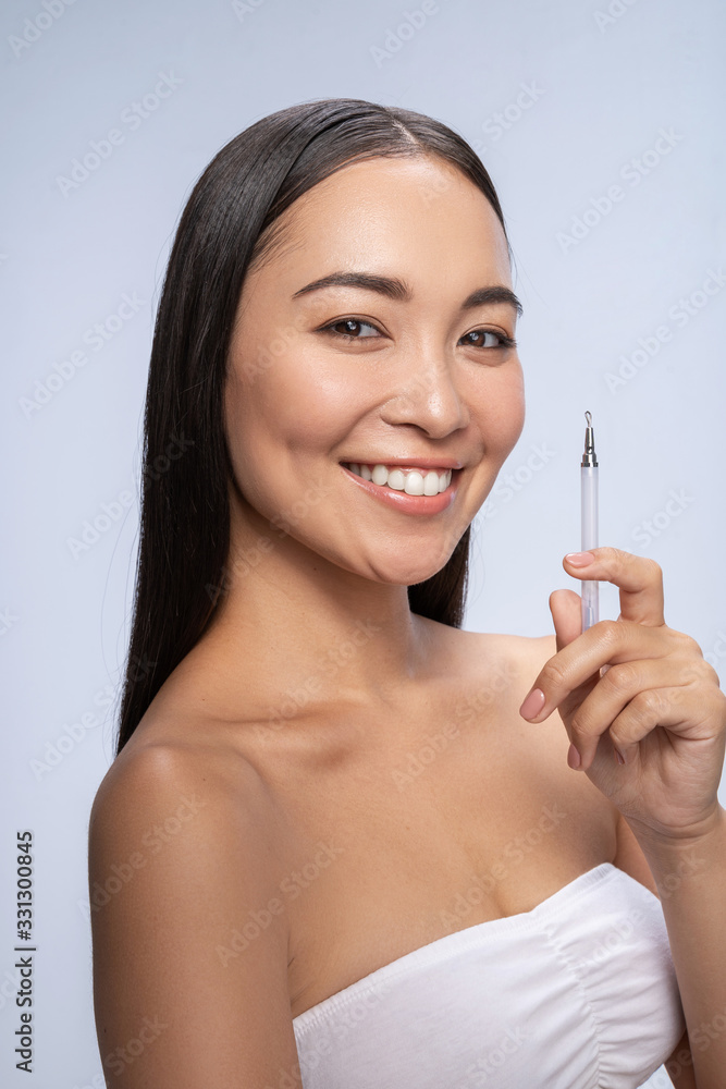 Smiling pretty woman posing with comedone extractor Smiling pretty woman posing with comedone extractor