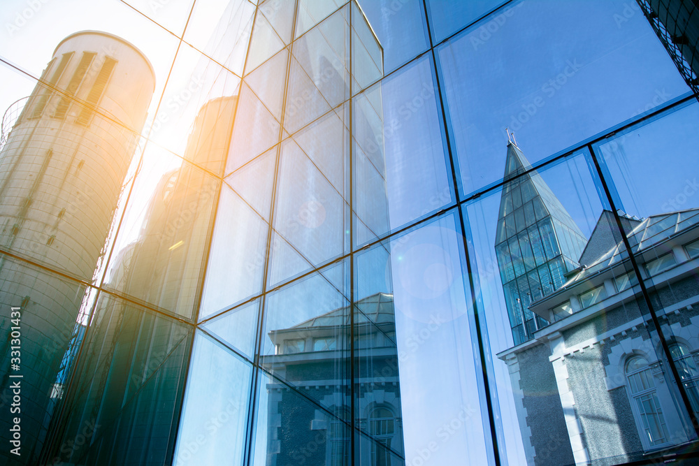 Obraz premium Office building glass facades on a bright sunny day with sunbeams in the blue sky. 