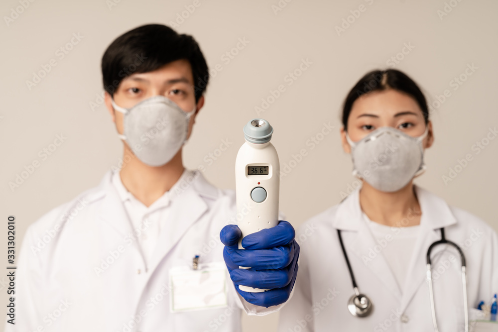 Image of asian doctors in protective masks holding medical equipment Image of asian doctors in protective masks holding medical equipment