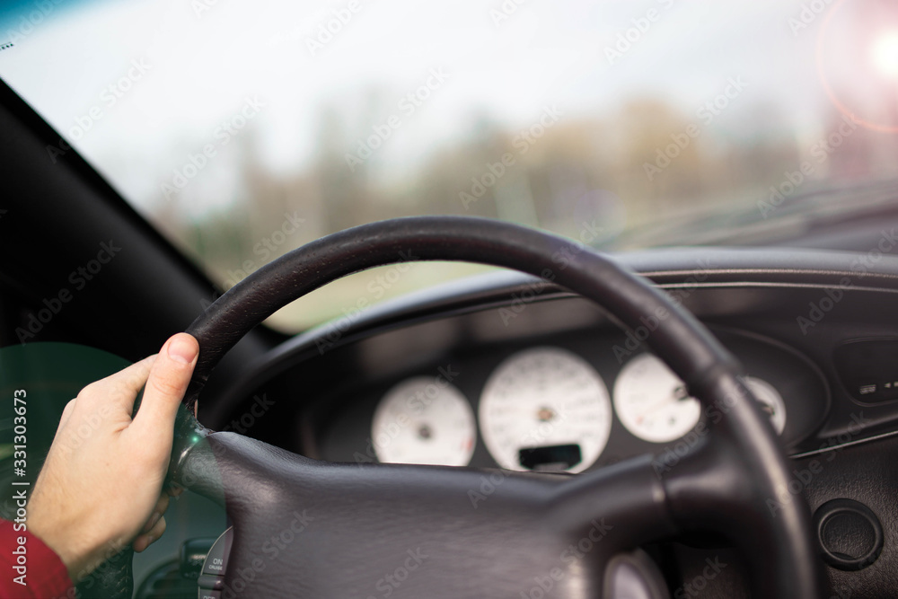 hand of the driver on the steering wheel in the summer, the concept of delivery of a driver’s license