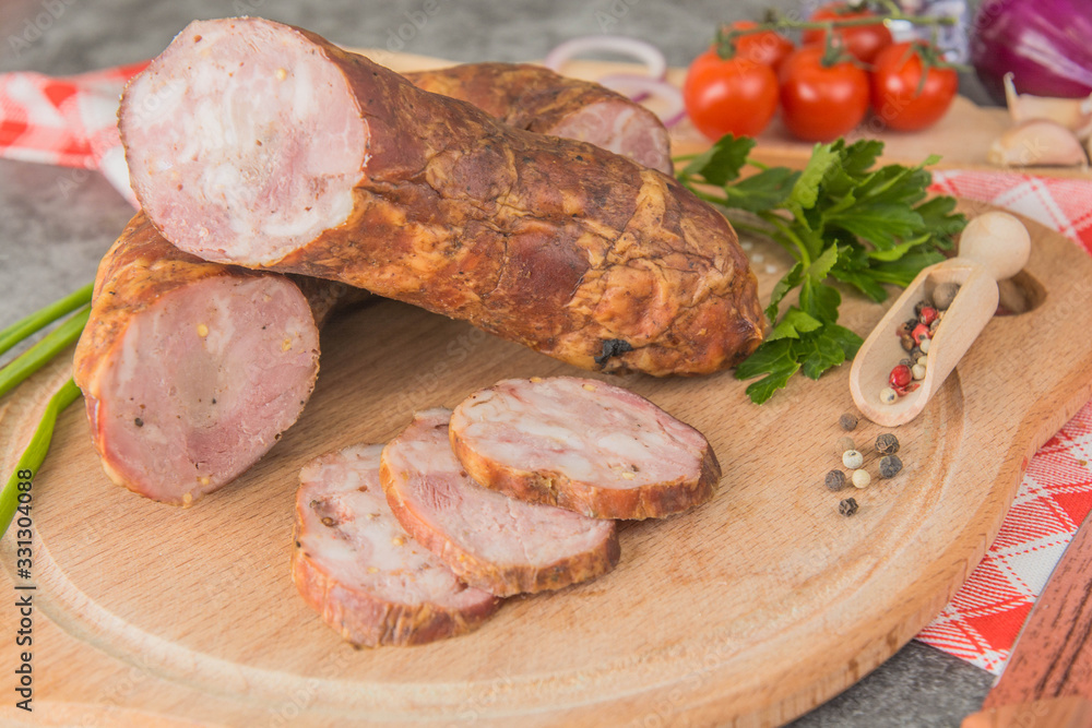Sausage with minced meat, cut into small pieces on a wooden board with spices and herbs. Close-up Sausage with minced meat, cut into small pieces on a wooden board with spices and herbs. Close-up