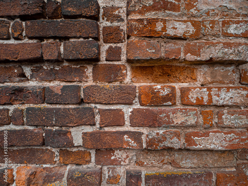 Old red grunge brick wall looks like texture. Close-up view of the brickwork with different shape bricks.