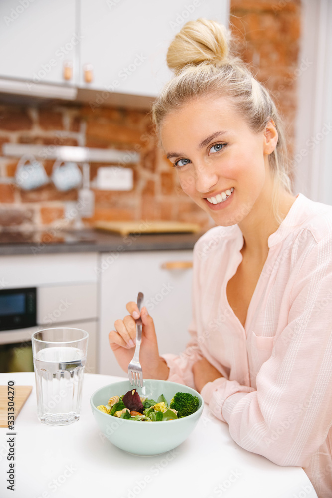 Portrait of a beautiful woman eating salad and smiling.