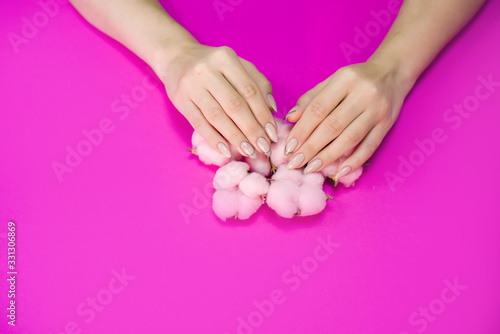 Beautiful women s manicure in delicate tones  on a bright background with gently pink cotton.