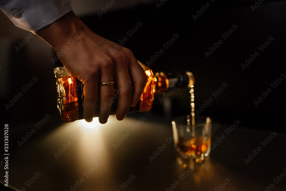 Groom, man pour whiskey into a glass. Groom wedding preparation. Close-up Groom, man pour whiskey into a glass. Groom wedding preparation. Close-up