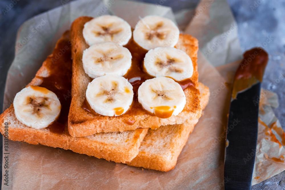 Two delicious toasts with salted caramel and bananas on the table. Two delicious toasts with salted caramel and bananas on the table.