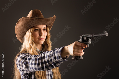 Lovely blonde posing in studio with a cowboy hat and a gun © Lapidus