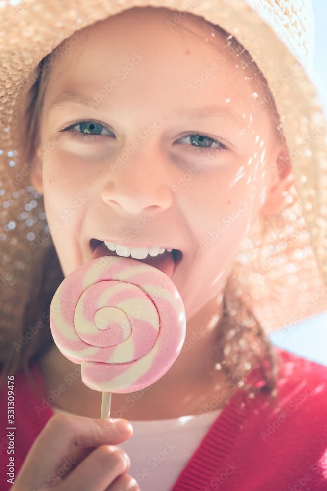 Little girl in a straw hat licking a pink and white lollipop Stock ...