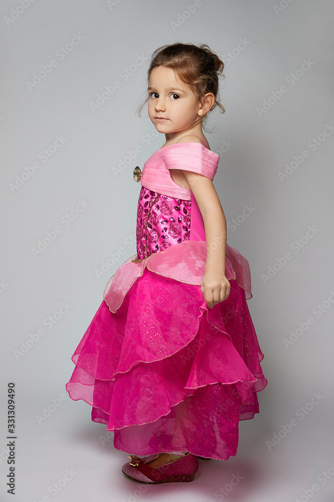 A young girl in a pink dress fans her dress A young girl in a pink dress fans her dress