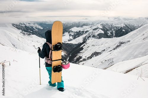 Female tourist with snowboard and walking sticks on mountain top photo