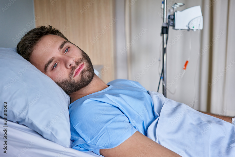 Sick young man recuperating on a bed in a hospital Sick young man recuperating on a bed in a hospital