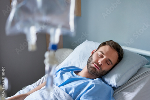 Sick young man receiving an intravenous treatment in a hospital