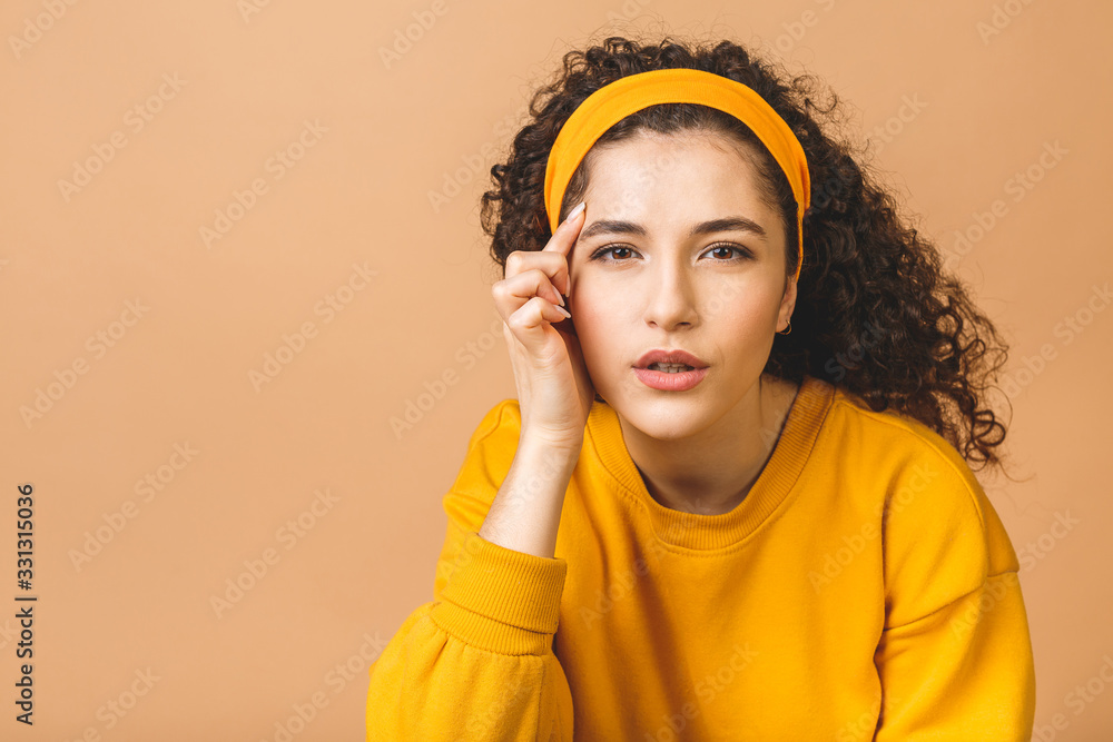 Φωτογραφία Beauty portrait of an astonished attractive curly woman examining her face while holding a mirror isolated over beige background