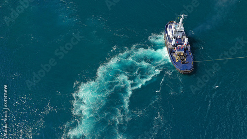 Aerial drone top down photo of tug boat manoeuvring to guide large vessel to port © aerial-drone