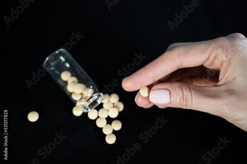 Woman holds small antiviral pill in hand. Drug researched in laboratory speeds up coronavirus recovery in early trials of COVID-19. Active against virus SARS-CoV-2 and ebola disease curation