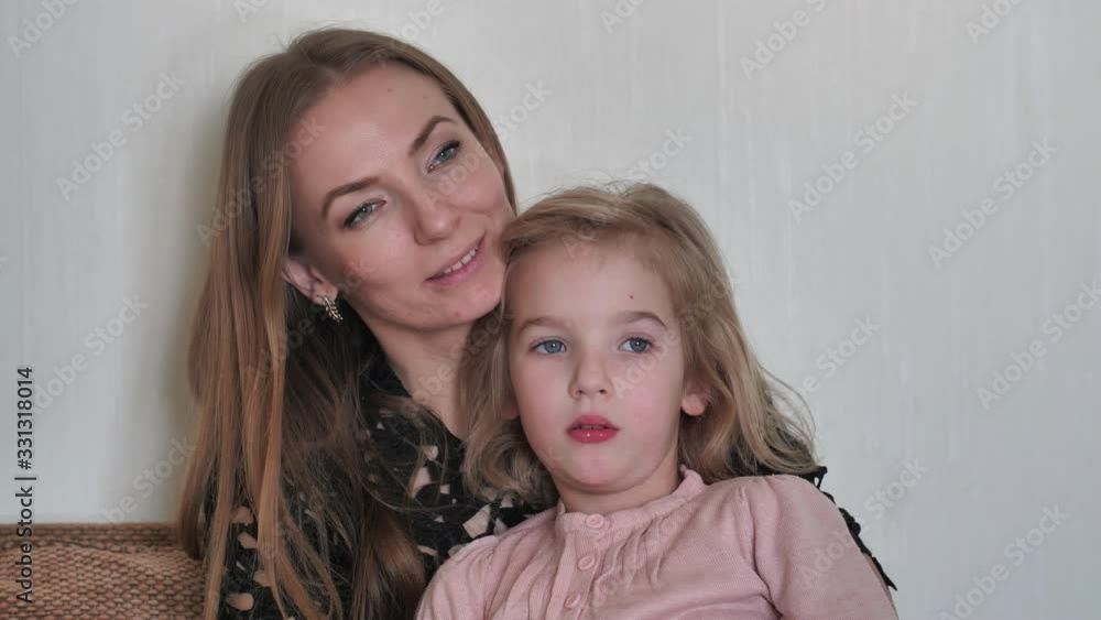 Mother with daughter sits on a sofa at home. Mother with daughter sits on a sofa at home.