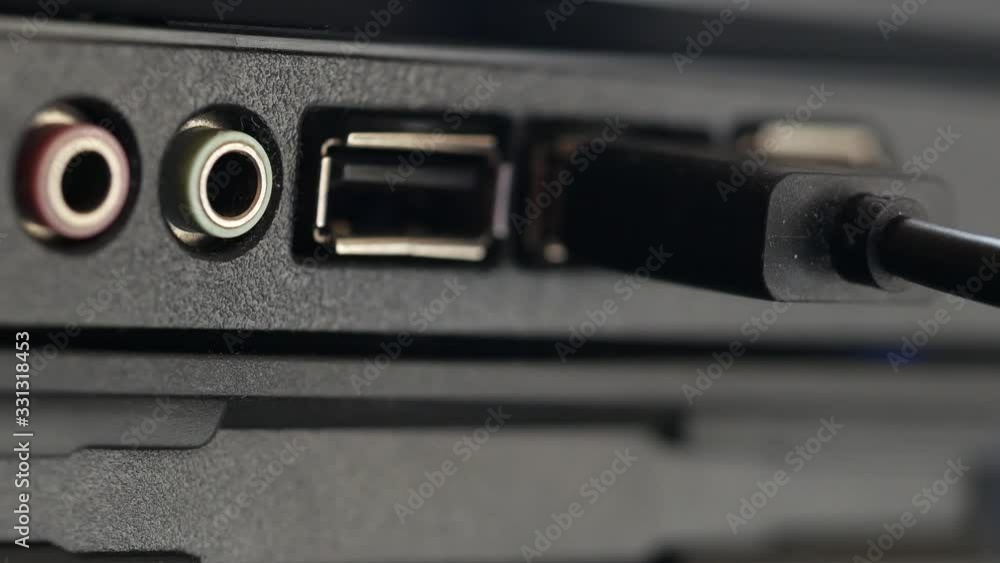 USB cable is inserted into socket. Black panel with colored connectors for microphone and headphones, and also Universal Serial Bus connection ports close-up. Macro of hand inserting black cable USB cable is inserted into socket. Black panel with colored connectors for microphone and headphones, and also Universal Serial Bus connection ports close-up. Macro of hand inserting black cable