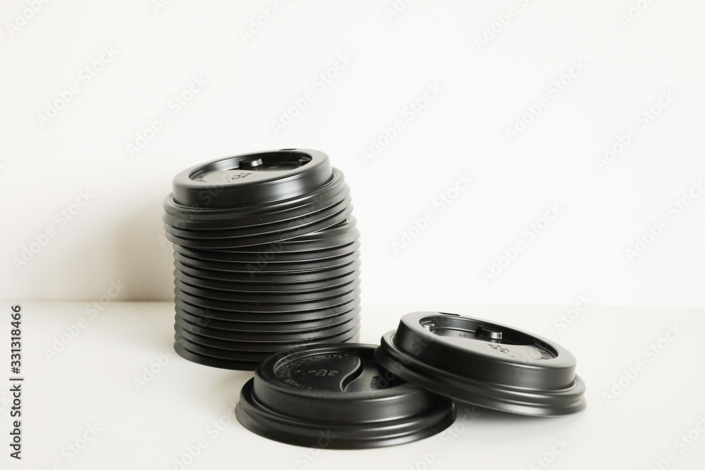 Black coffee cup plastic lids, stacked on a white background Black coffee cup plastic lids, stacked on a white background