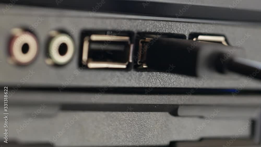 USB cable is inserted into socket. Black panel with colored connectors for microphone and headphones, and also Universal Serial Bus connection ports close-up. Macro of human hand inserting black cable USB cable is inserted into socket. Black panel with colored connectors for microphone and headphones, and also Universal Serial Bus connection ports close-up. Macro of human hand inserting black cable