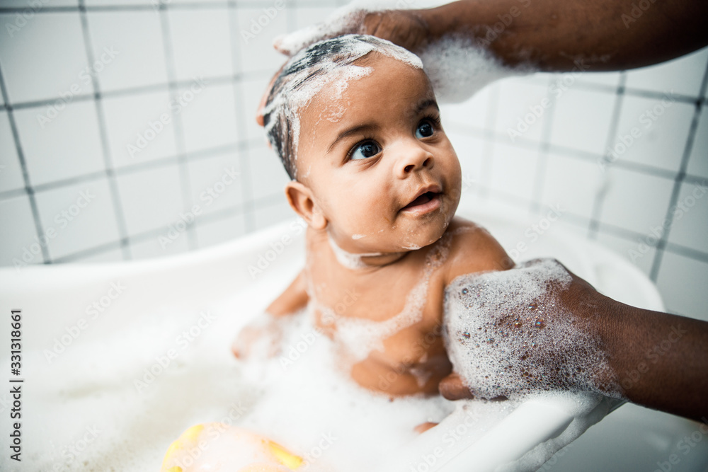 Afro American man washing hair of adorable newborn child Afro American man washing hair of adorable newborn child