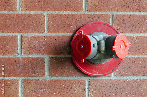 fire extinguisher sprinkler connection on red brick wall