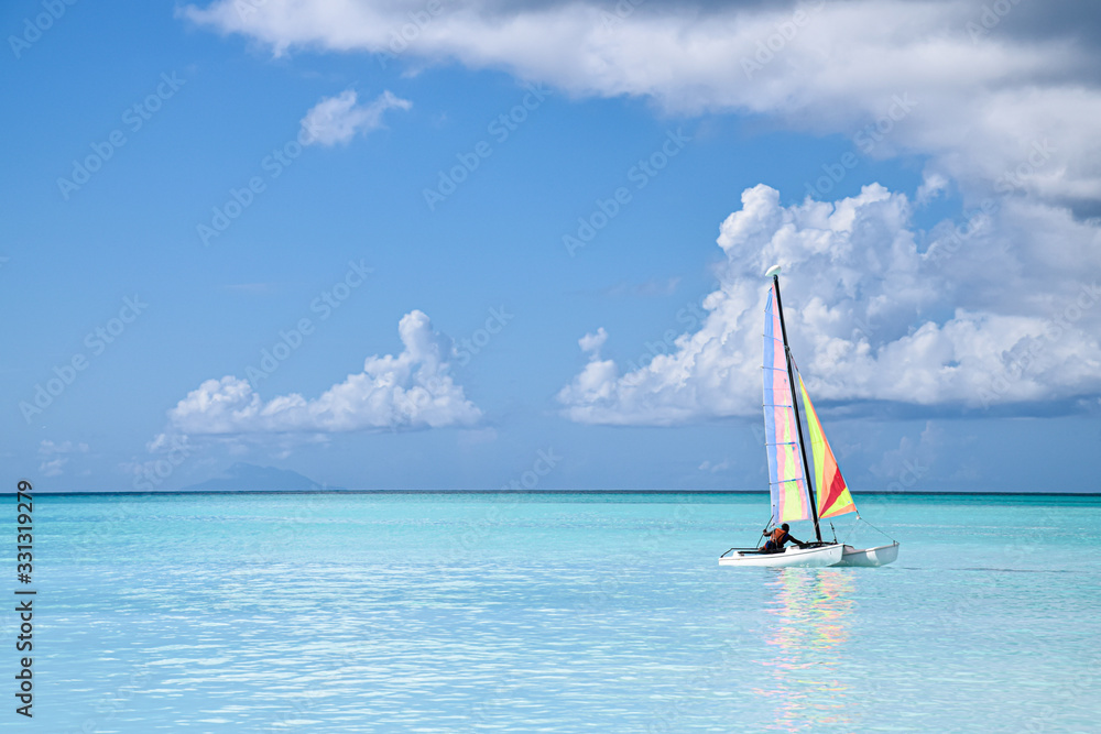 Naklejka premium Caraibi 01 - cielo e mare azzurro con vela e riflessi nell'acqua