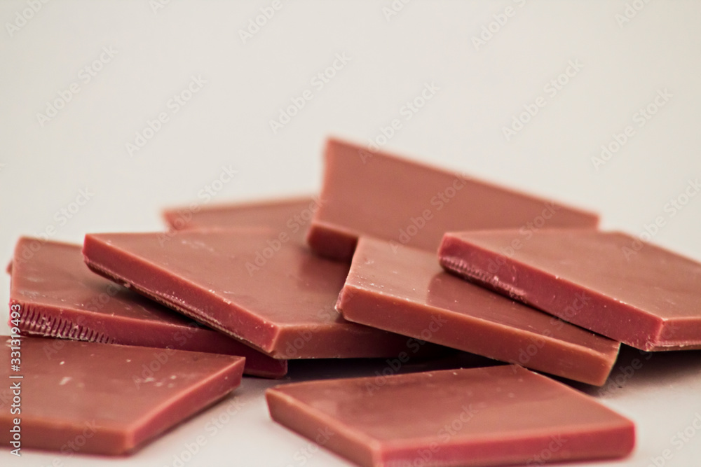 Natural Pink Color Ruby Chocolate slices of heap on white with copy space. Natural Pink Color Ruby Chocolate slices of heap on white with copy space.