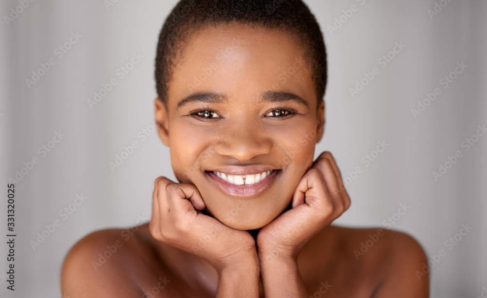 Naklejka premium Young woman smiling while resting her face in her hands