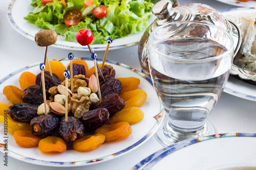 Traditional Ramadan Dinner-Iftar Table with dry date fruits and a glass of water Traditional Ramadan Dinner-Iftar Table with dry date fruits and a glass of water