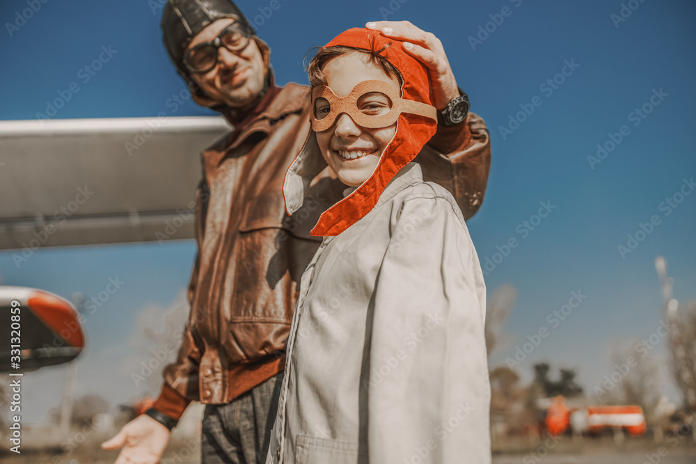Happy little boy in aviator glasses standing near his dad