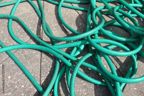 Messy Green Garden Hose outdoors on cement ground