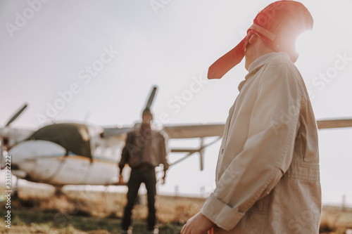 Little kid in aviator hat standing outdoors