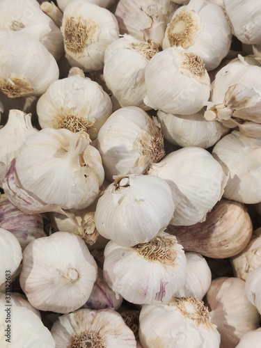 Garlic Cloves and Bulb in vintage wooden bowl.White garlic pile texture. Fresh garlic on market table closeup photo,