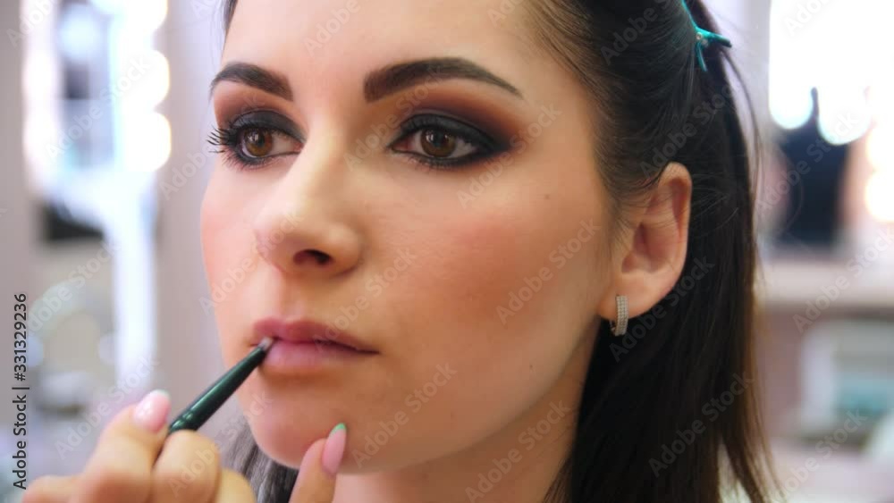 The make-up artist paints the lips of young girl. Make-up artist doing makeup for the young girl, close-up. The make-up artist paints the lips of young girl. Make-up artist doing makeup for the young girl, close-up.