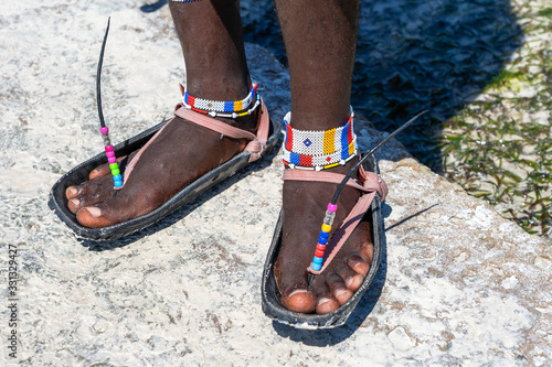 Tribal masai legs with a colorful bracelet and sandals made of car tires, close up. Island of Zanzibar, Tanzania, Africa