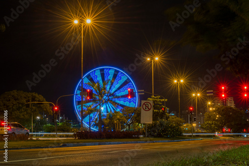 Long exposure of colorful ferris wheel and light trails on the expressway road at night.