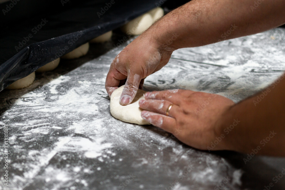 table with flour and chef's hands kneading homemade bread