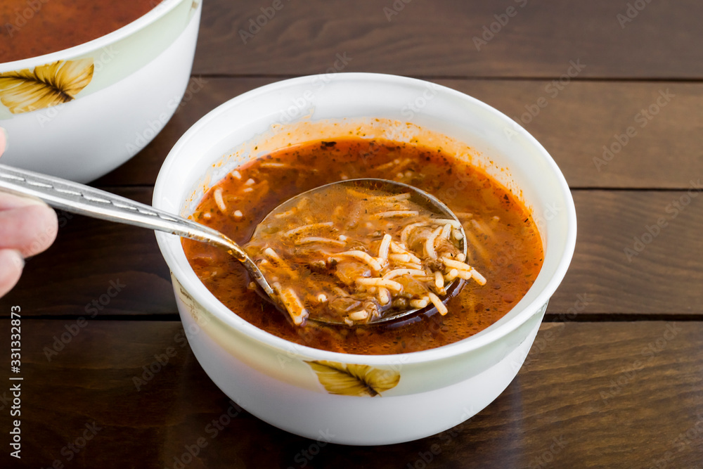 Traditional Turkish Vermicelli Soup, serving with metal ladle, on wooden table Traditional Turkish Vermicelli Soup, serving with metal ladle, on wooden table