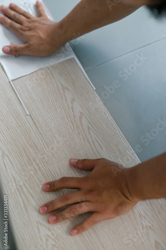 A person installing new vinyl tile floor, a DIY home project.