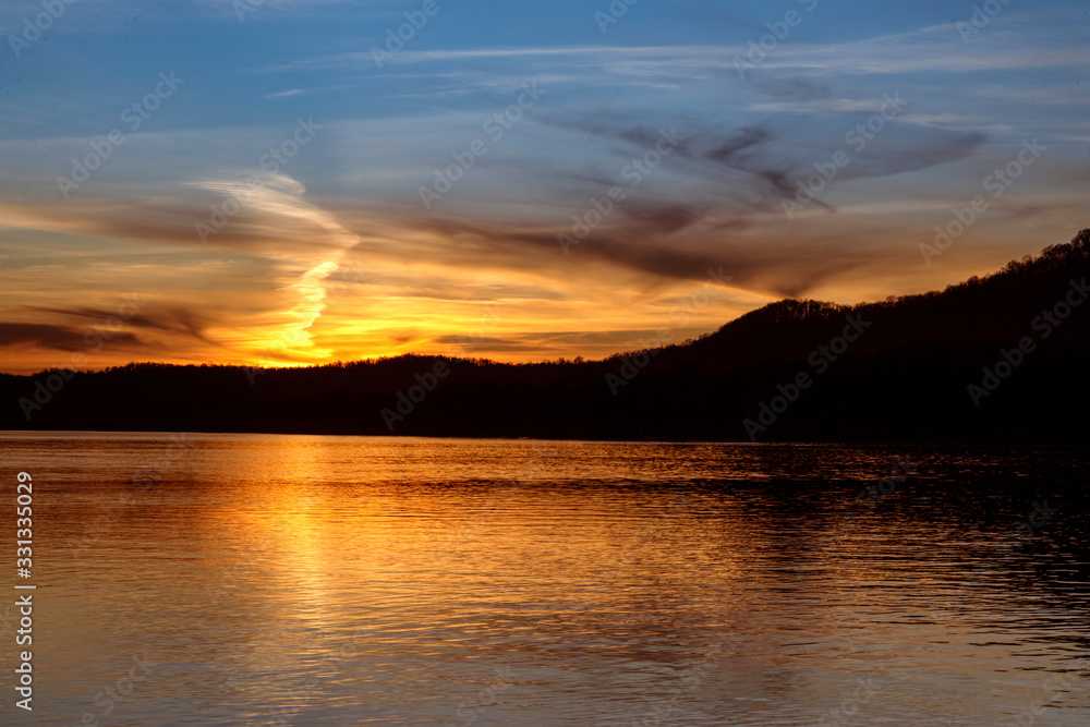 The sunset paints the sky over the hills of the Ohio River Valley with the reflection of fading evening light upon the calm water as photographed from the West Virginia shore. The sunset paints the sky over the hills of the Ohio River Valley with the reflection of fading evening light upon the calm water as photographed from the West Virginia shore.