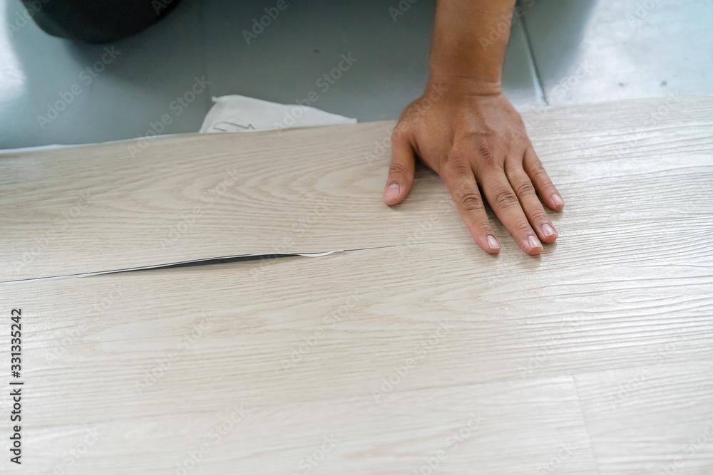 A person installing new vinyl tile floor, a DIY home project. A person installing new vinyl tile floor, a DIY home project.