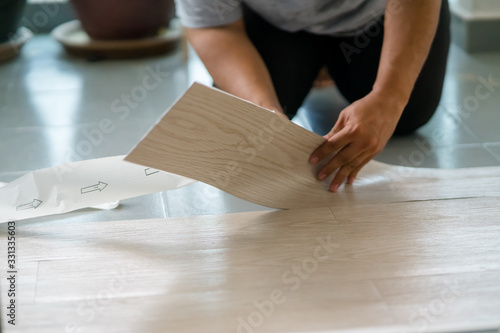 A person installing new vinyl tile floor  a DIY home project.