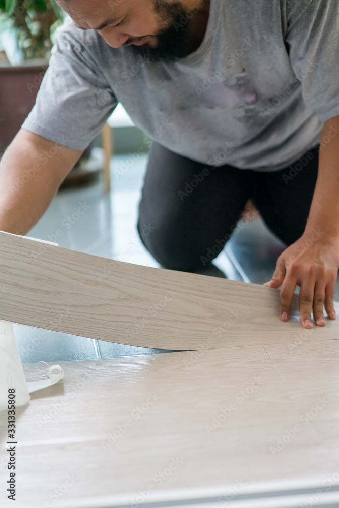 Kuala Lumpur, Malaysia - March 1, 2020: A man installing new vinyl tile floor, a DIY home project. Kuala Lumpur, Malaysia - March 1, 2020: A man installing new vinyl tile floor, a DIY home project.