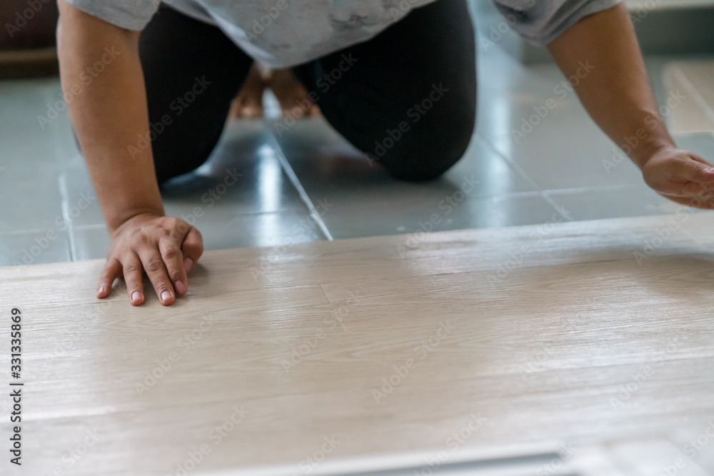 A person installing new vinyl tile floor, a DIY home project. A person installing new vinyl tile floor, a DIY home project.