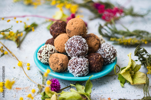 Sweet vegan protein cocoa chocolate oatmeal with dates, carob, coconut meat, sesame seeds and banana energy balls or bars. Healthy dessert. Truffles on plate
