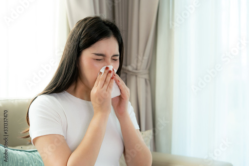 Asian woman sick and sad with sneezing on nose and cold cough on tissue paper because influenza and weak or virus bacteria from dust weather or smoke for medical..