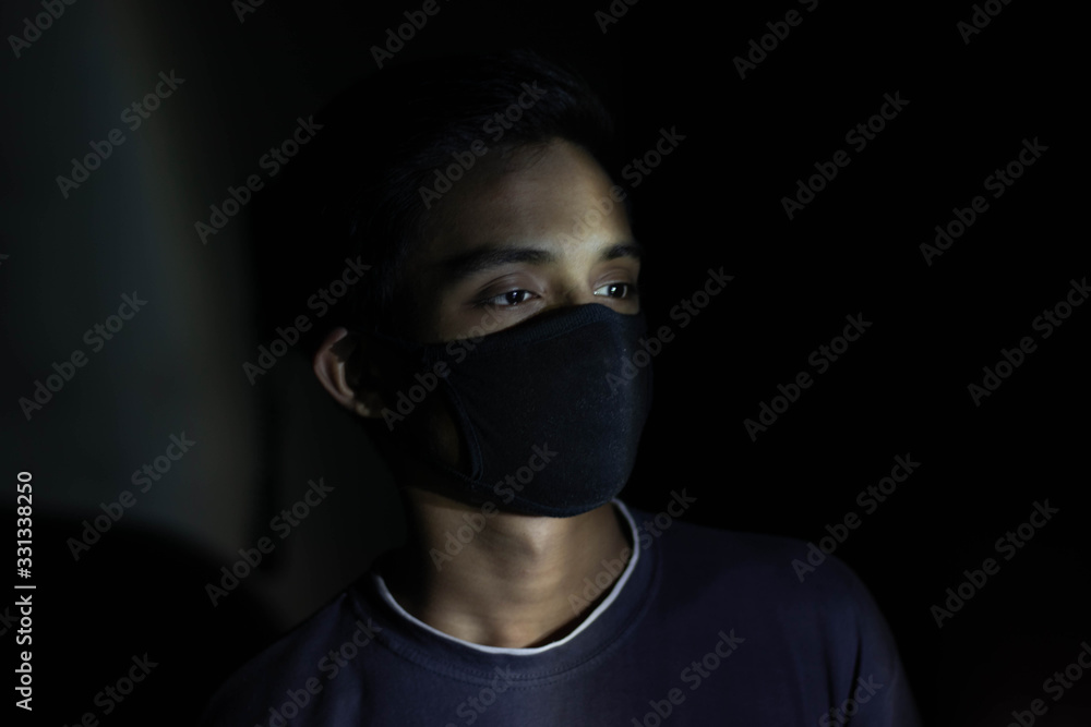 Fotografia do Stock: Young sick boy wears a black safety mask over dark  background.Mask prevents corona virus and air pollution dust.Portrait of  young boy wearing a mask and crying.Corona virus mask protection