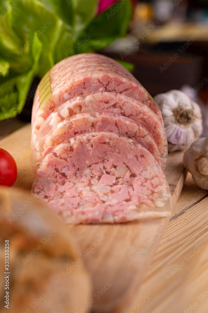 Sliced brawn on wooden cutting board. Headcheese. Pork cold cuts, meat product. 