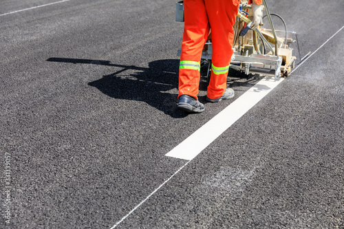 Road workers use hot-melt scribing machines to painting dividing line on asphalt road surface in the city.